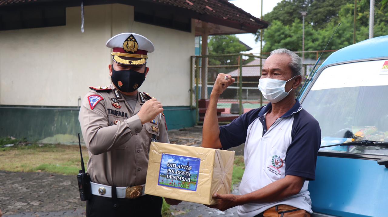 Kasat Lantas Polresta Denpasar Kompol Taufan Rizaldi bagikan sembako. (Foto : PMJ/Ist). 