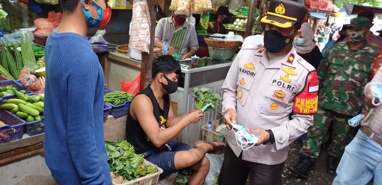 Anggota Polsek Kembangan membagikan masker dan melakukan penyemprotan disinfektan di Pasar Loksem Taman Aries. (Foto: PMJ News) 