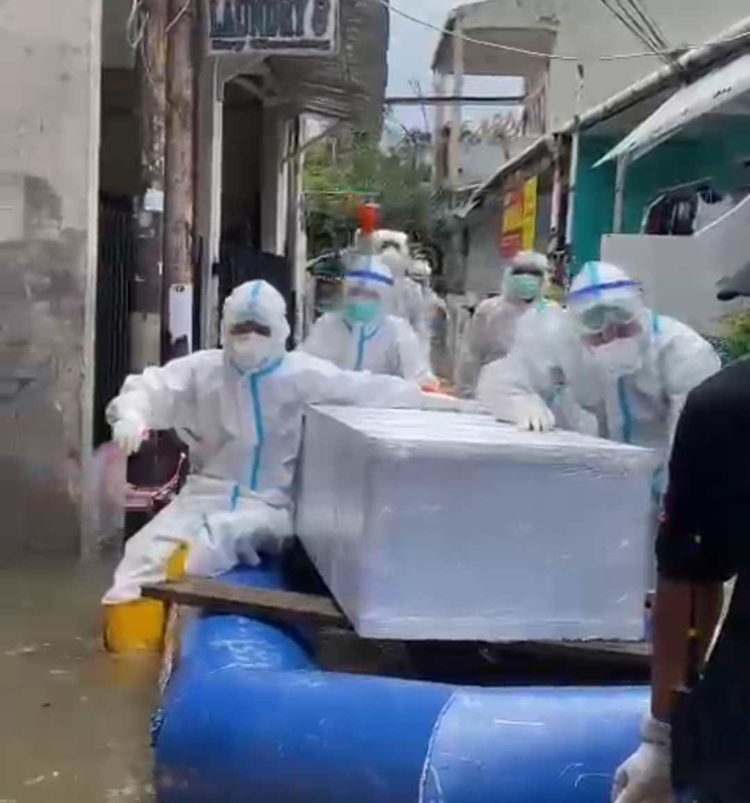 Tim pemulasaran jenazah covid Polda Metro Jaya evakuasi jenazah di tengah banjir. (Foto: PMJ News). 