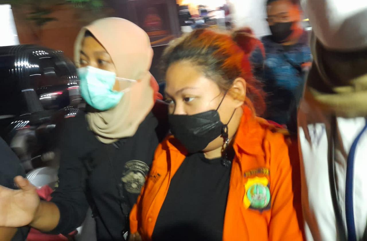 Olivia Nathania menggunakan baju tahanan berwarna orange dengan didampingi penyidik Ditreskrimum Polda Metro Jaya. (Foto: PMJ News/ Yeni).