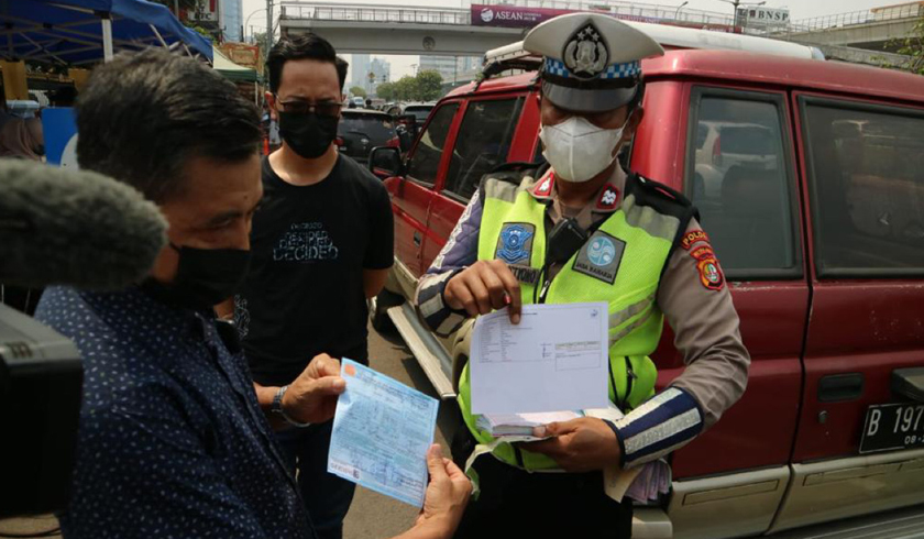 Seorang petugas kepolisian memberikan sanksi tilang uji emisi kepada pengendara. (Foto: PMJ News/Dok DLH DKI Jakarta)