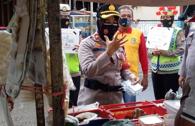 Kapolsek Bekasi Kota, Kompol Armayni memberikan sosialisasi penerapan prokes dan membagikan masker di pasar tradisional. (Foto: PMJ News).