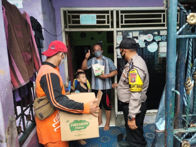 Jajaran Polsek Pademangan memberikan bantuan berupa susu kepada anak-anak yang terdampak Covid-19. (Foto: PMJ News). 
