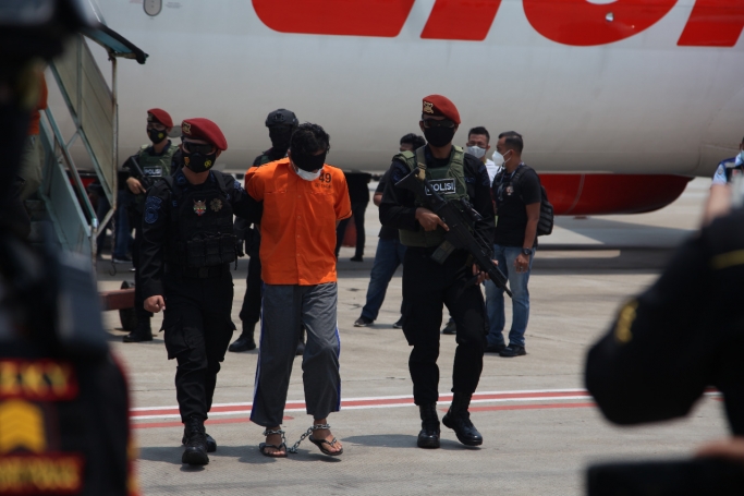 Anggota tim Densus 88 Antiteror mengawal ketat 22 terduga teroris di Parking Stand K13 Area Apron Terminal Cargo Bandara Soekarno-Hatta. (Foto: PMJ News). 
