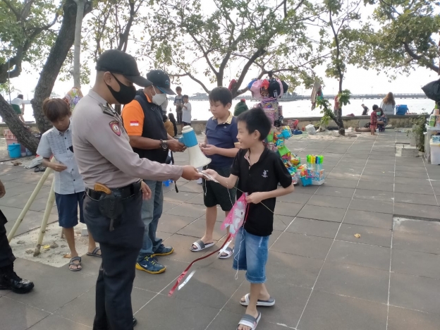 Anggota Polsek Pademangan bagikan masker untuk pengunjung Ancol yang tidak pakai masker. (Foto: PMJ News)