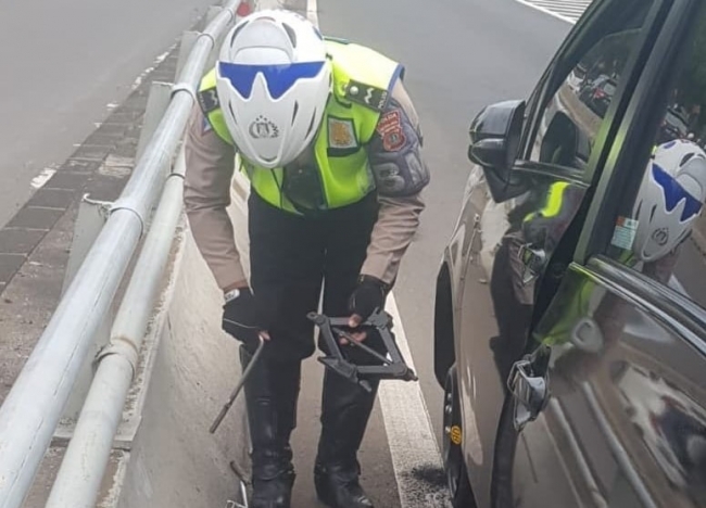 Aiptu Hendra Manik membantu pemgendara yang alami ban kempes saat melaksanakan pengaturan lalu lintas di offramp Slipi arah Tomang Jakarta Barat. (Foto: PMJ News)