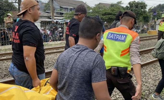 Petugas keamanan mengevakuasi jasad korban yang tewas tertabrak kereta. (Foto: Dok PMJ News)