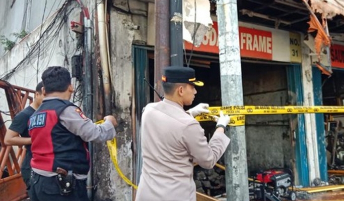 Petugas memasang garis polisi di lokasi kebakaran toko bingkai Jalan Mampang Prapatan, Jakarta Selatan. (Foto: PMJ News/Istimewa)