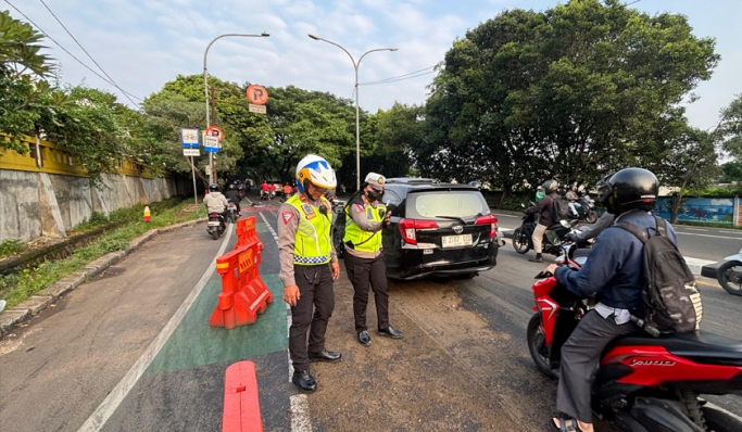 Anggota Satlantas Polres Metro Depok terjun ke lapangan untuk membersihkan tumpahan oli di Jalan Raya Juanda. (Foto: PMJ News)